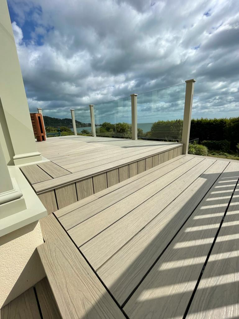 Light grey composite decking with glass balustrade sea view