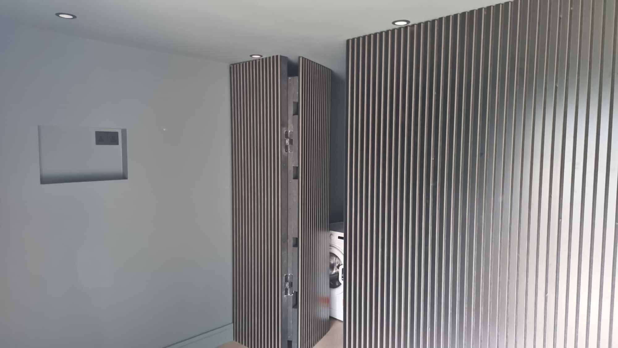 Slatted wall panelling and utility storage inside black garden room, Dublin