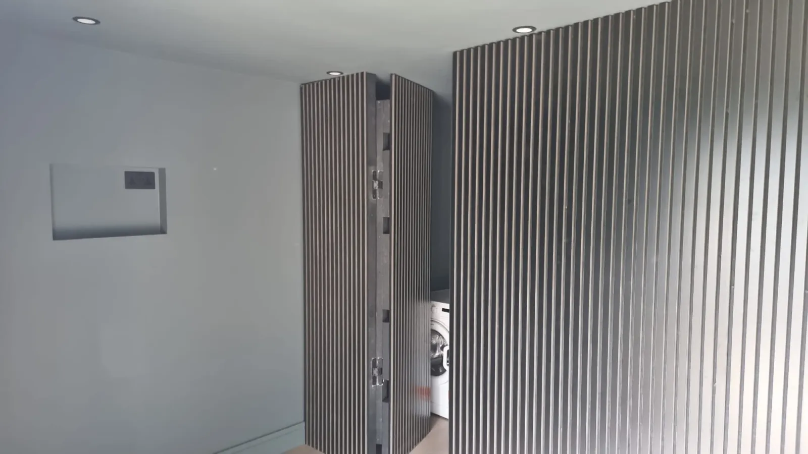 Slatted wall panelling and utility storage inside black garden room, Dublin