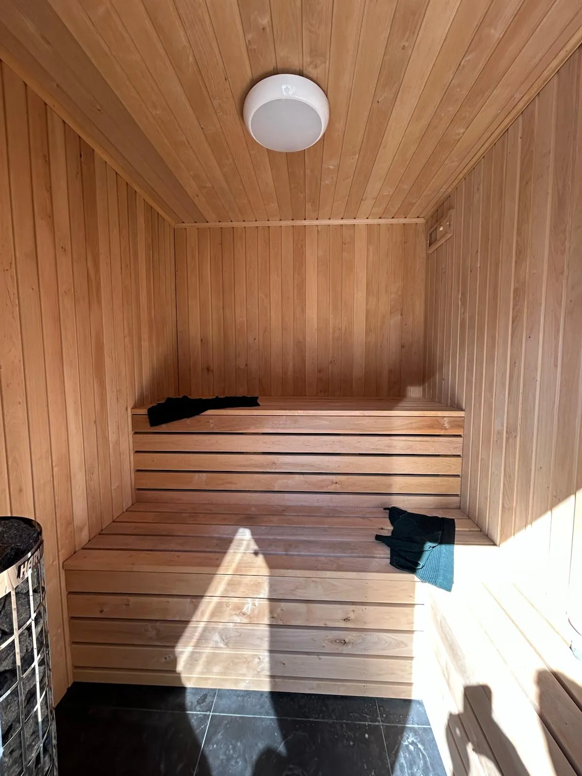 Cedar sauna interior with tiered benches and Harvia heater