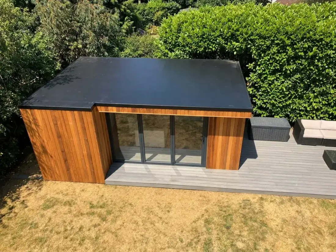 Cedar garden room with flat EPDM roof and composite decking — aerial angle