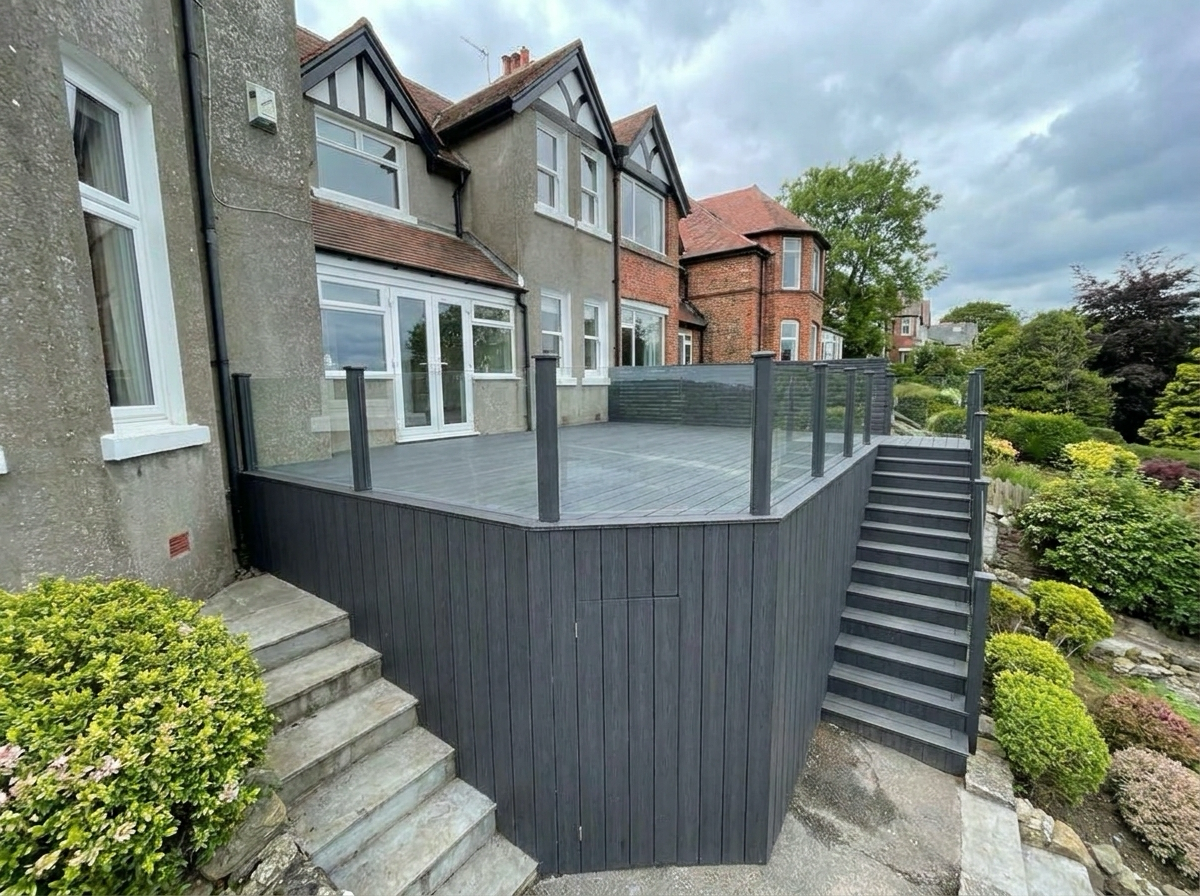 Full-width charcoal composite deck with frameless glass balustrade — front angle