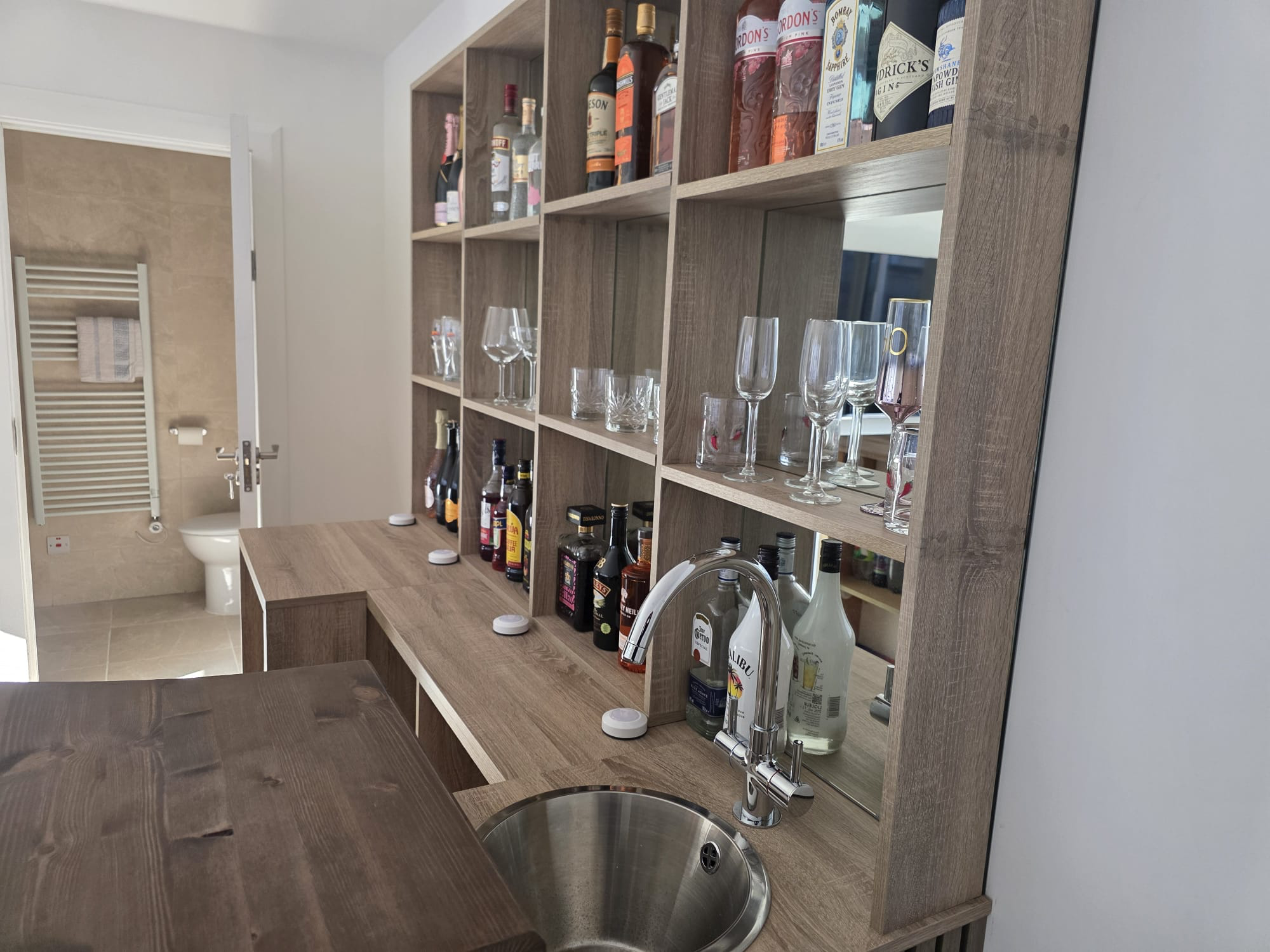Custom bar shelving unit with mirrored back and integrated sink