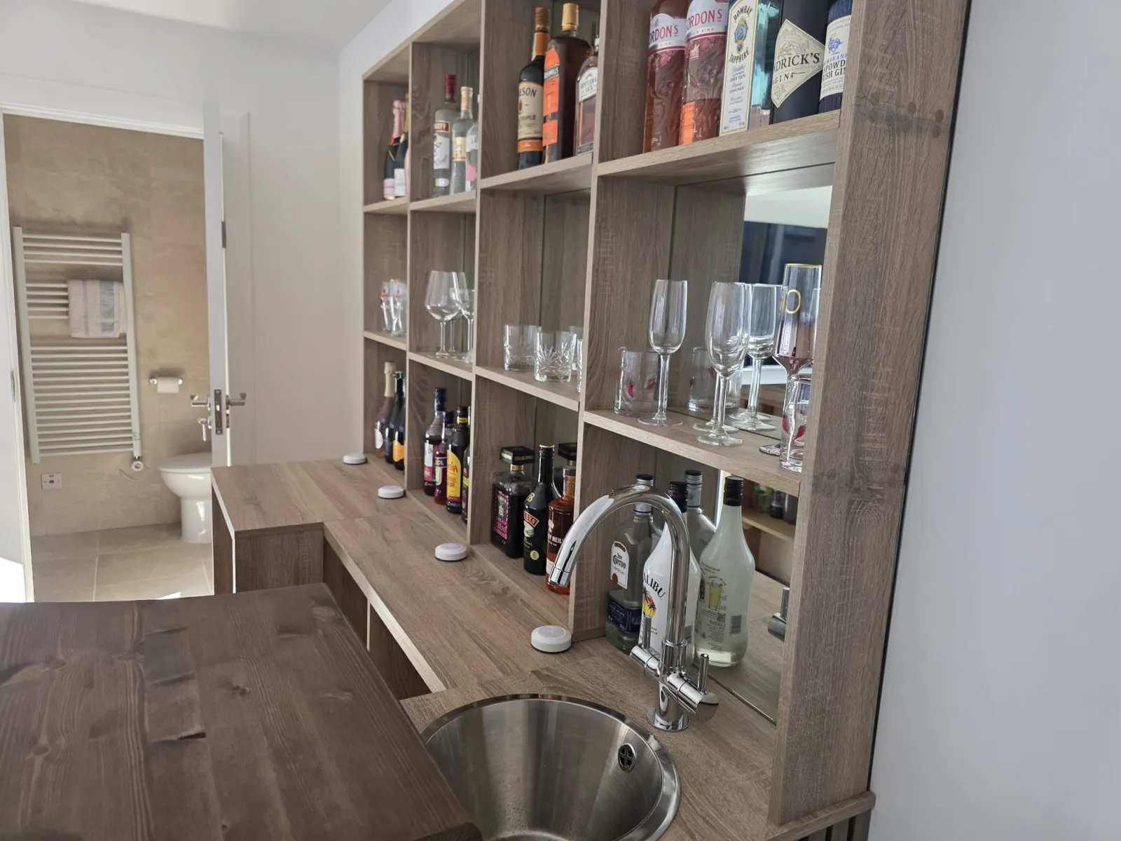 Custom bar shelving unit with mirrored back and integrated sink