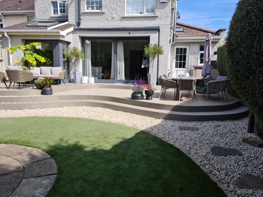 Large curved composite decking patio with outdoor furniture and gravel landscaping