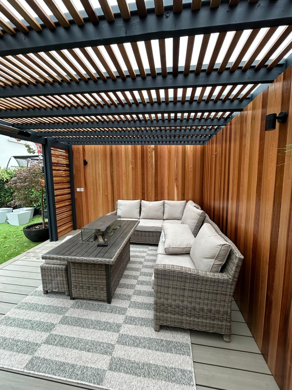 Under the pergola — cedar feature wall, fire pit table and lounge seating