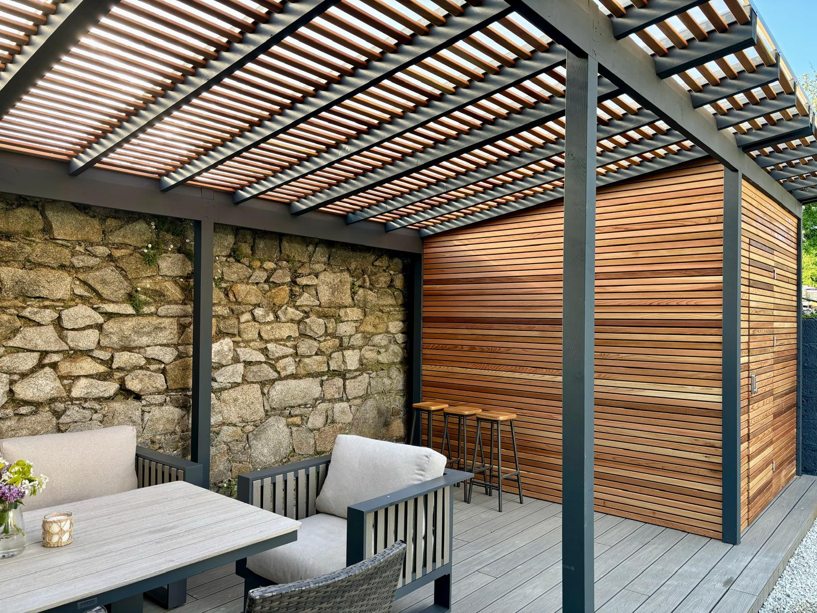 Inside the pergola — cedar screening, stone wall and bar stools
