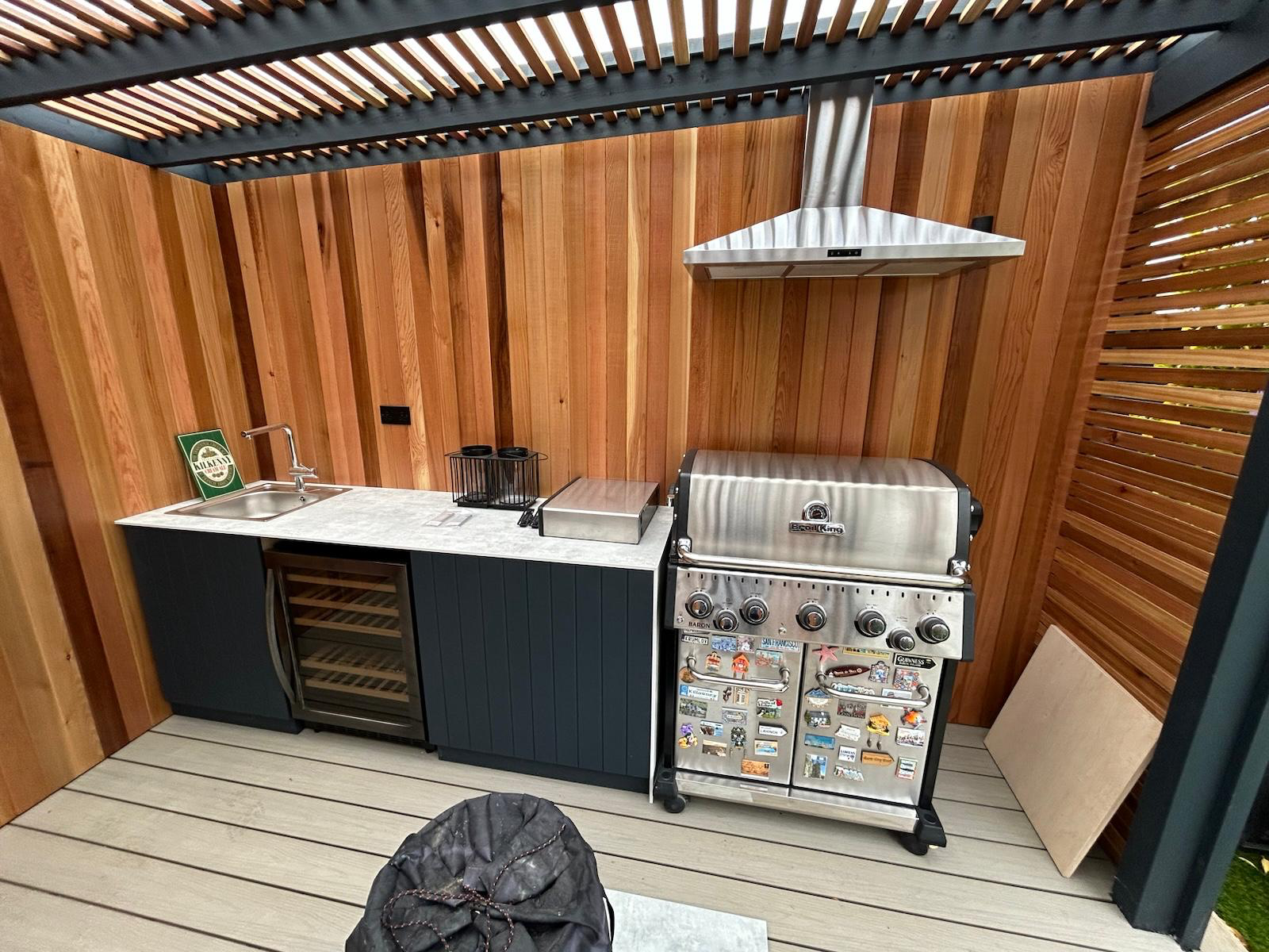 Outdoor kitchen with BBQ and wine fridge under cedar pergola Dublin